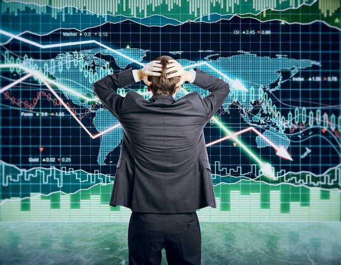 Person in front of falling stock market graph.