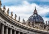 St. Peters Basilica dome with statues and clouds.