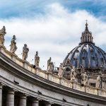 St. Peters Basilica dome with statues and clouds.