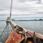 Sailboat bow facing calm sea and distant mountains