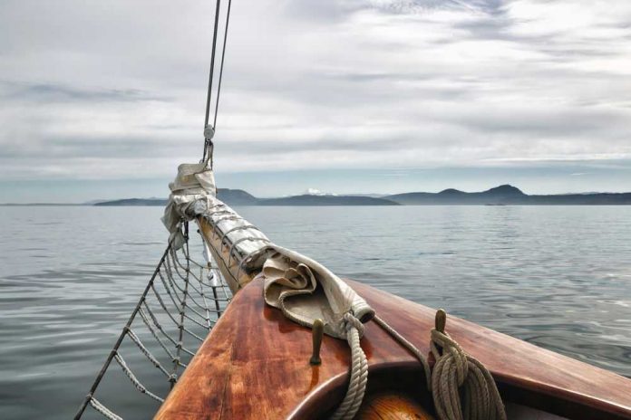 Sailboat bow facing calm sea and distant mountains