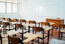 Teacher BANNED Over Migration Talk Empty classroom with desks, chairs, and whiteboard.