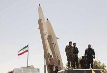 Cluster Missiles Turn Streets Into Minefields Military personnel beside missiles and Iranian flag.