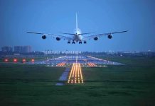 An airplane approaching the runway at night with landing lights illuminated