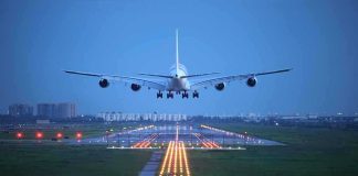 An airplane approaching the runway at night with landing lights illuminated