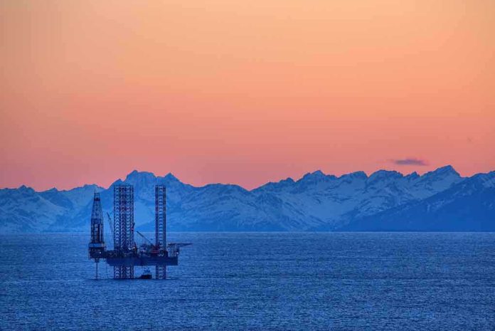 shutterstock_139270961.jpg An oil rig in the ocean with a backdrop of mountains during sunset