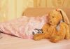A cozy bedroom scene featuring a stuffed bunny and pink bedding