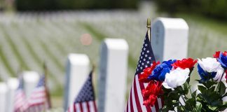 American flags and flowers placed at graves in a cemetery