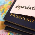 Stack of passports with a note labeled deportation on top, placed on a map