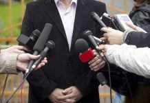 Cringe Opener Hijacks Governor’s Interview A group of microphones surrounding a person at a press conference