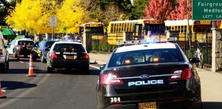 GUNFIRE Erupts—Principal’s Body Blocks the Killer Police cars and school buses on a road.