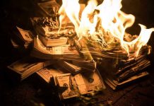 Stacks of hundred dollar bills burning in flames.