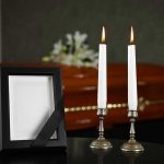 Casket, photo frame, and two lit candles.