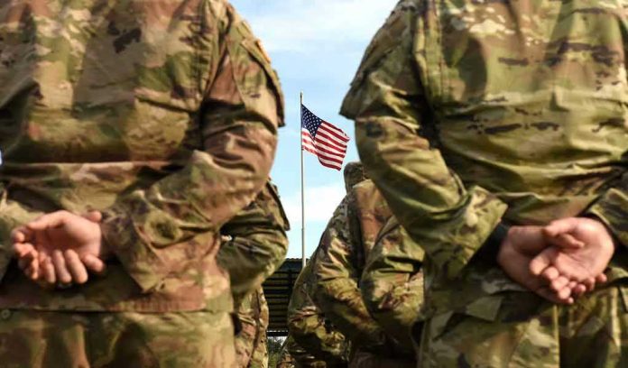 Soldiers stand in formation with American flag in background.