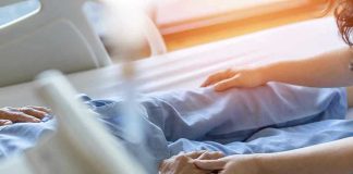 Euthanasia EXPLOSION — One in 25 Deaths Now Hospital patient holding visitors hand reassuringly.