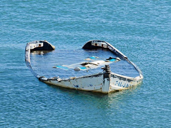 Half-submerged, weathered, abandoned boat floating on calm water.