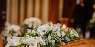 Flower arrangement on a wooden casket at a funeral.