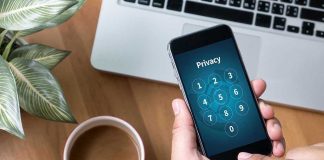 Typing privacy passcode on smartphone near laptop and coffee.