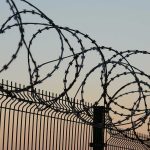 Barbed wire fence against sunset sky background.