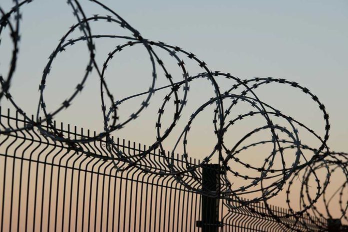 771028372 Barbed wire fence against sunset sky background.