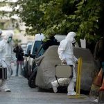 Investigators in hazmat suits carrying equipment cases.