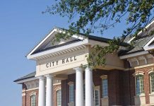 Exterior view of a city hall building with columns and a clear blue sky