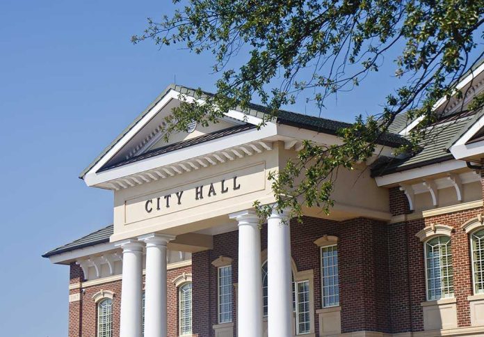 Exterior view of a city hall building with columns and a clear blue sky