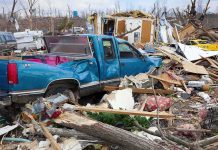 A blue truck surrounded by debris and destruction from a natural disaster