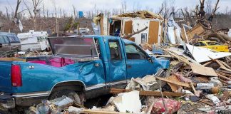 A blue truck surrounded by debris and destruction from a natural disaster