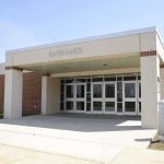 Entrance of a modern school building with glass doors and a brick facade