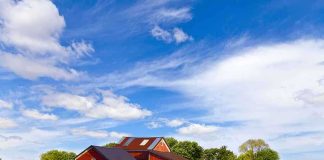 A vintage tractor in front of a red barn on a sunny day