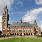 A historic building with a tall clock tower and ornate architecture set against a cloudy sky