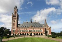 A historic building with a tall clock tower and ornate architecture set against a cloudy sky