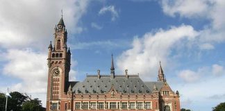 Dutch Court SHOCKS Asylum Seekers A historic building with a tall clock tower and ornate architecture set against a cloudy sky