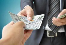 Two hands exchanging cash in a business setting