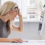 A woman with blonde hair showing a surprised expression while looking at a computer