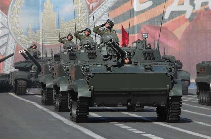 1702004938 Tanks with military personnel in street parade formation.