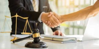 Hands shaking over legal documents with gavel and scales.