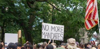 Idaho Raises Stakes With Harshest Law In Country Crowd holds No More Mandates sign at protest.