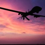 Silhouette of a drone against a colorful sunset.