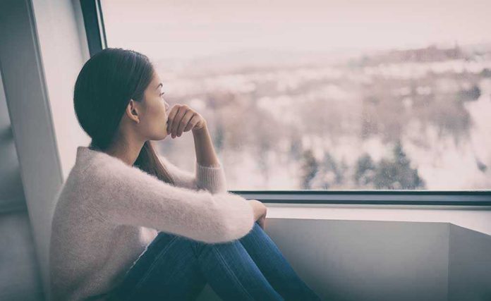 Person sitting and looking out a window at snow