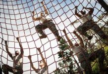 People climbing a red rope net outdoors.