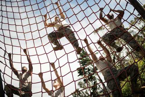 People climbing a red rope net outdoors.