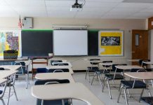 Empty classroom with desks, projector, and chalkboard.