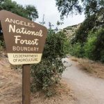 Sign marking the boundary of Angeles National Forest along a dirt path