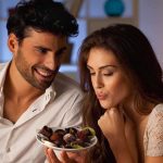 A couple sharing a plate of desserts in a cozy indoor setting