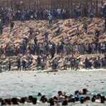 Thousands of migrants swim around the border from Morocco into Ceuta, Spain
