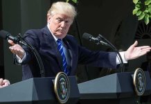 man at podiums with arms outstretched during outdoor press event