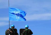 UN flag above peacekeepers in blue helmets
