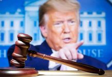 judge’s gavel with a blurred person pointing in the background